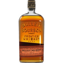 A spicy Old Fashioned with bitters bottles nearby on a dark wooden bar
