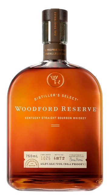 Golden bourbon in a glass on a dark wood bar, warm window light